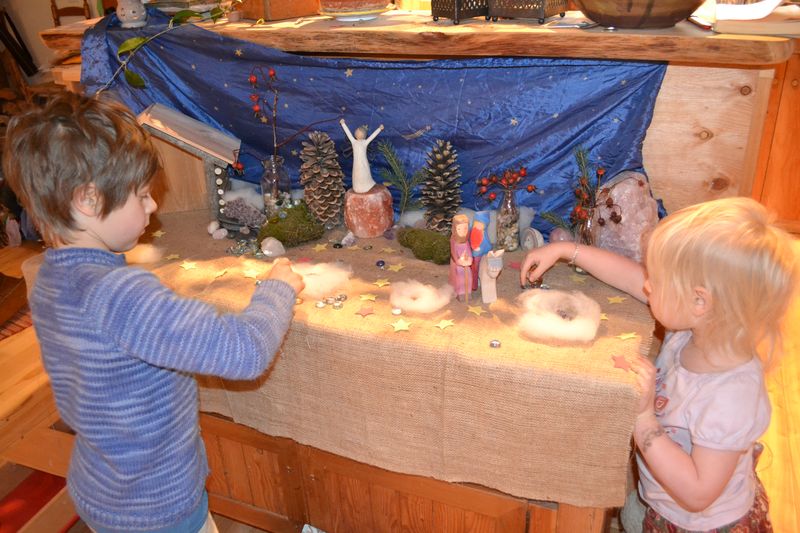 Children moving the figures in a Nativity Scene as they anticipate Christmas