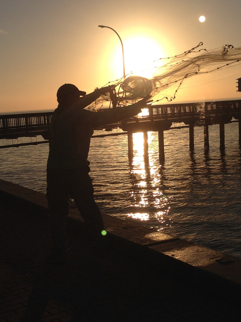 Local fisherman casting for bait on the Fairhope City Pier at sunset