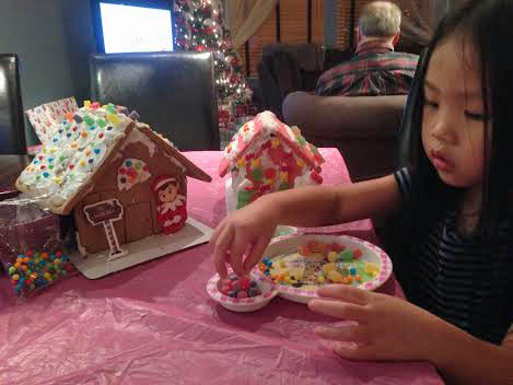 Grace adding candy decorations to gingerbread houses